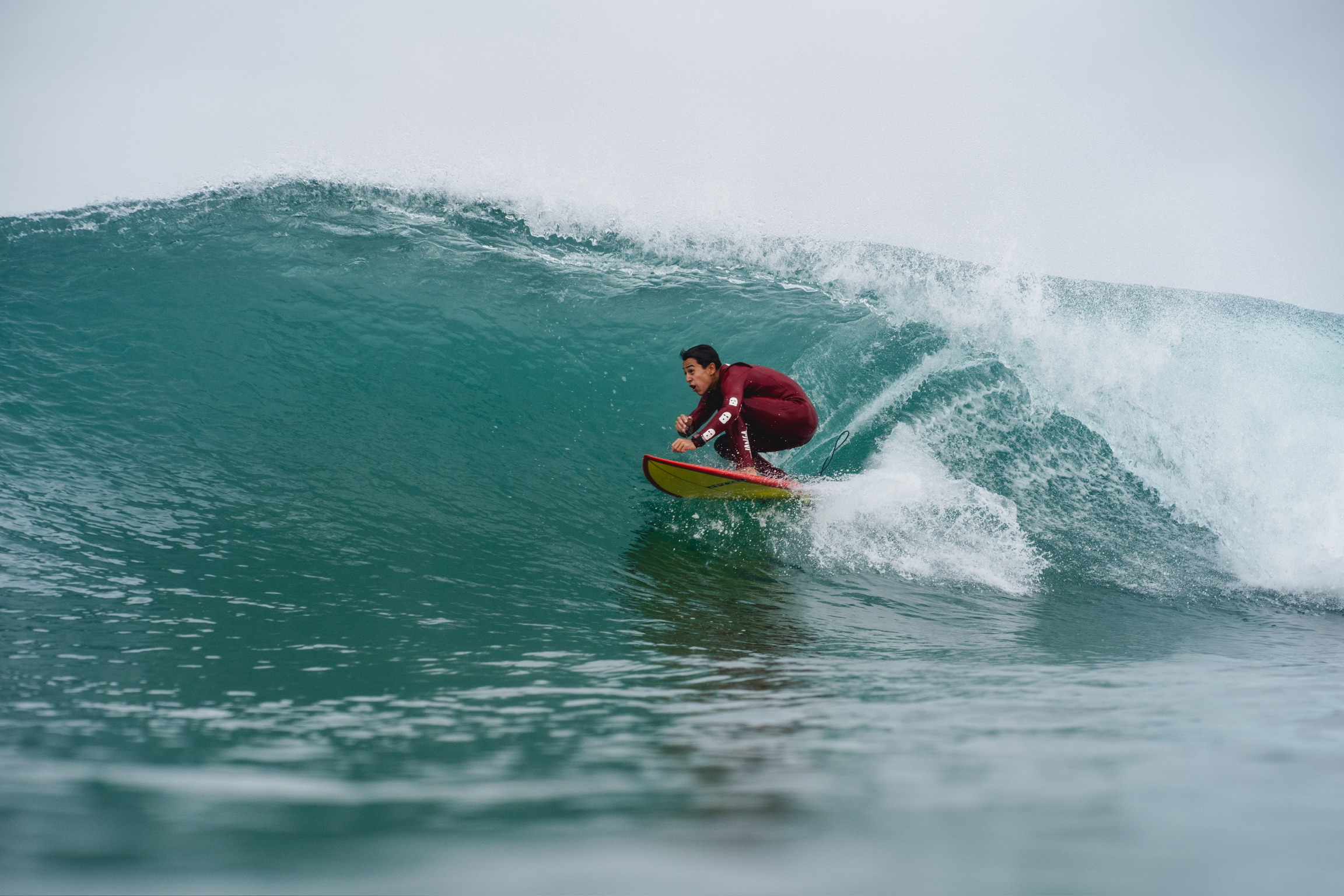 Professional surf photography showing surfer riding a perfect turquoise wave with dynamic action and spray